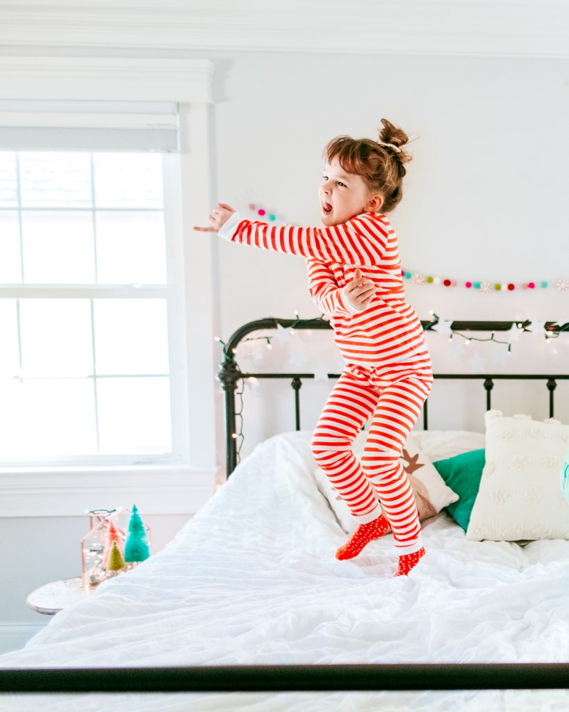 Little girl jumping in candy cane jammies