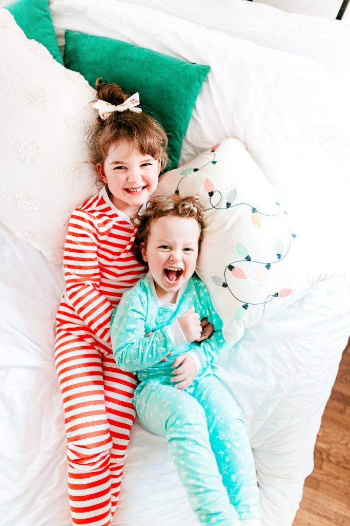 Brother and sister laughing in holiday jammies