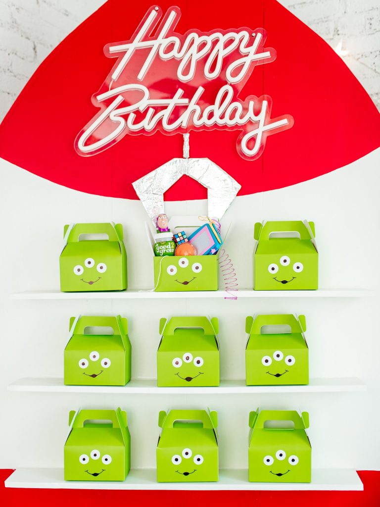 DIY foam board party favor wall shelves holding Toy Story alien favor boxes and juice bottles