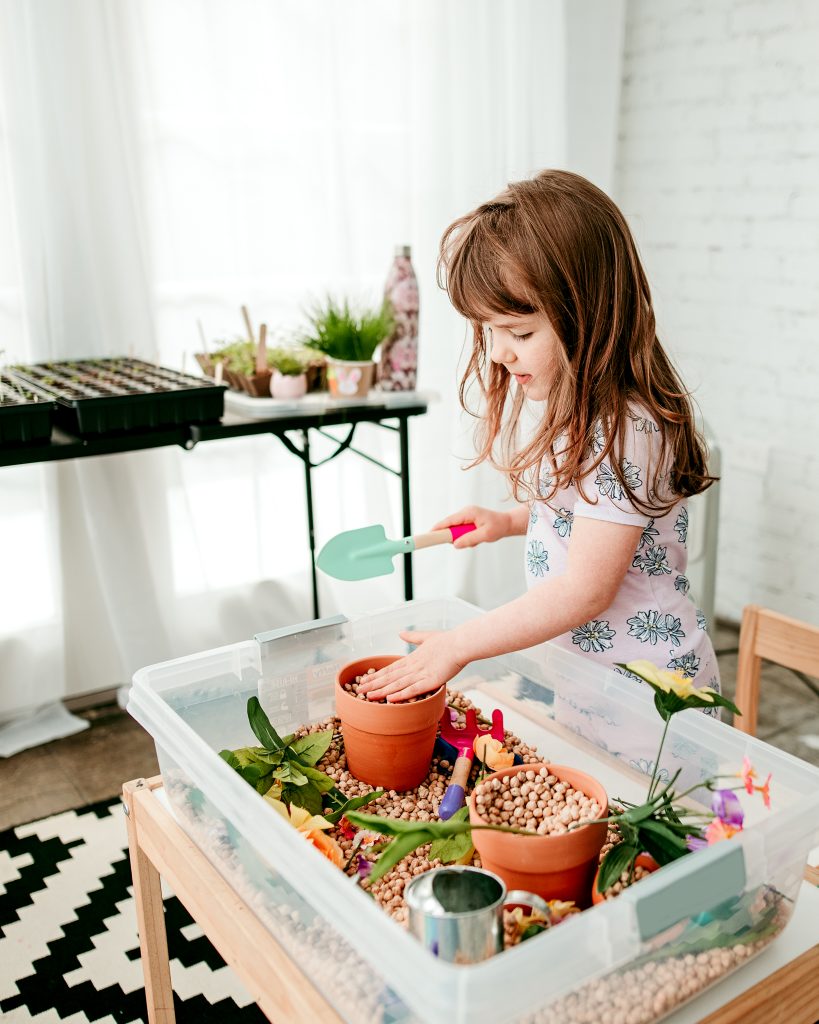 Indoor garden Sensory bin filled with pots, flowers, shovels, and watering cans