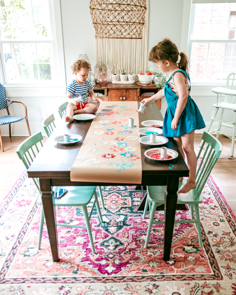 Make a 4th of July table runner using paint and paper roll firework stamps. A fun July art activity for kids!