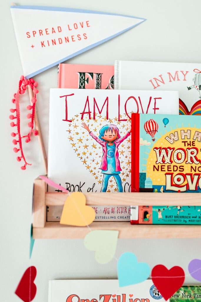 Favorite Valentine picture books for kids on a decorated wall bookshelf. 