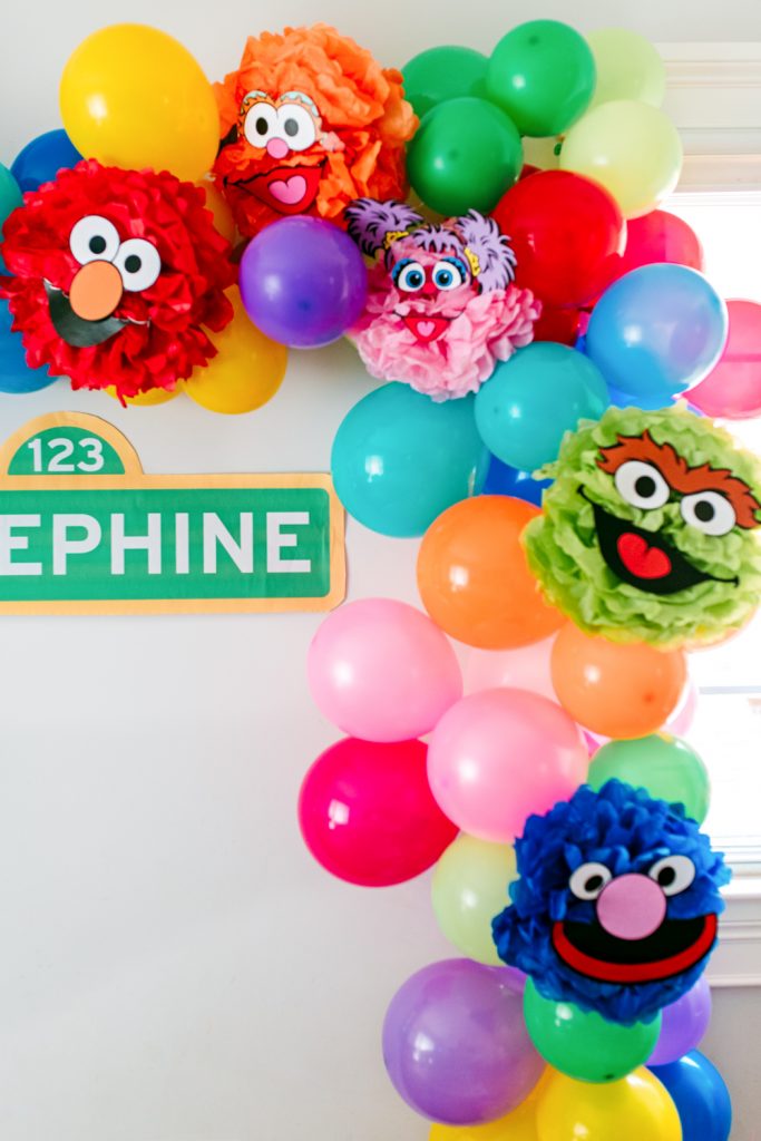DIY Birthday balloon garland with Sesame Street character pom poms. Instructions to make your own on my blog!